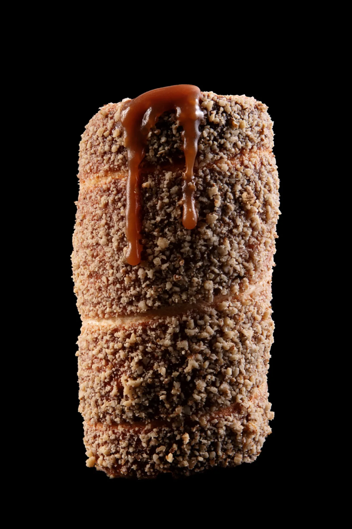 A walnut chimney cake with caramel dripping down the side