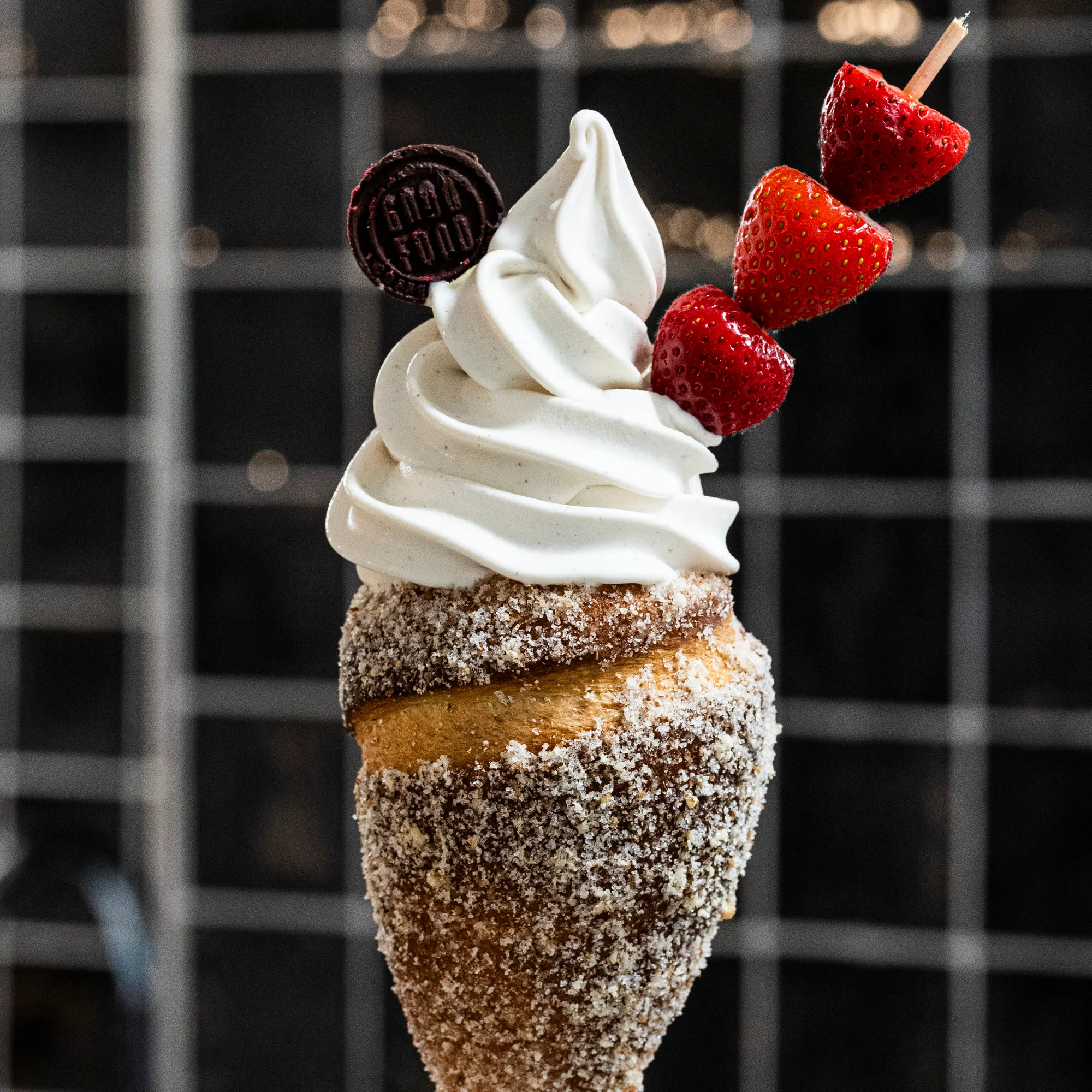 A chimney cone filled with vanilla gelato, with strawberries and a Good Food chocolate coin