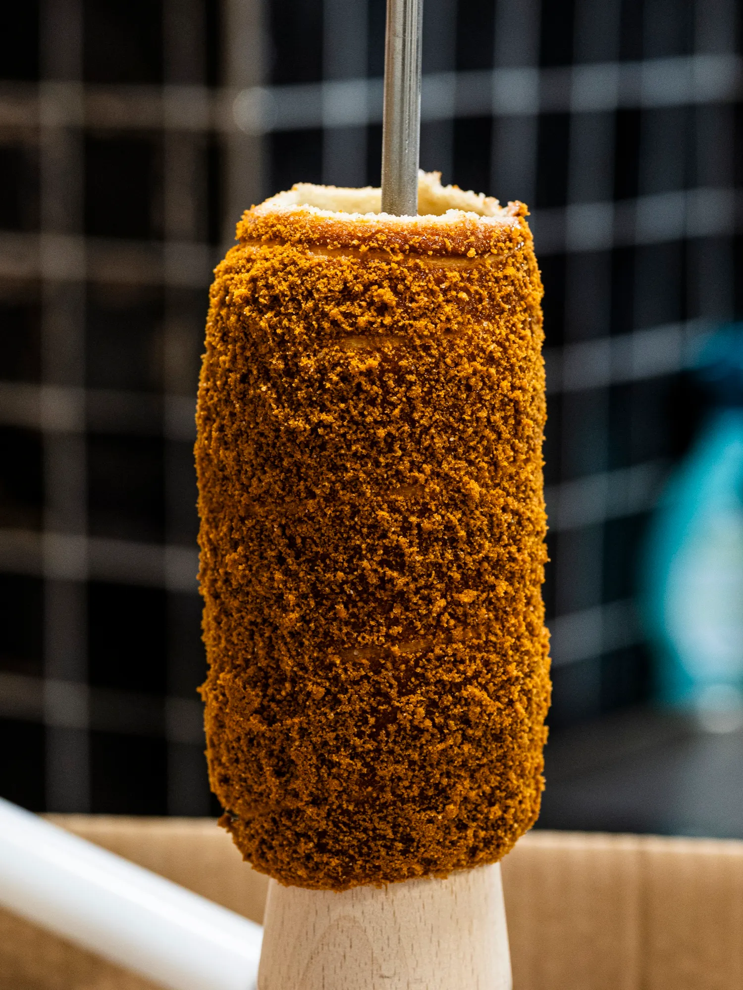 A chimney cake coated in caramelised biscuit crumb on the spit