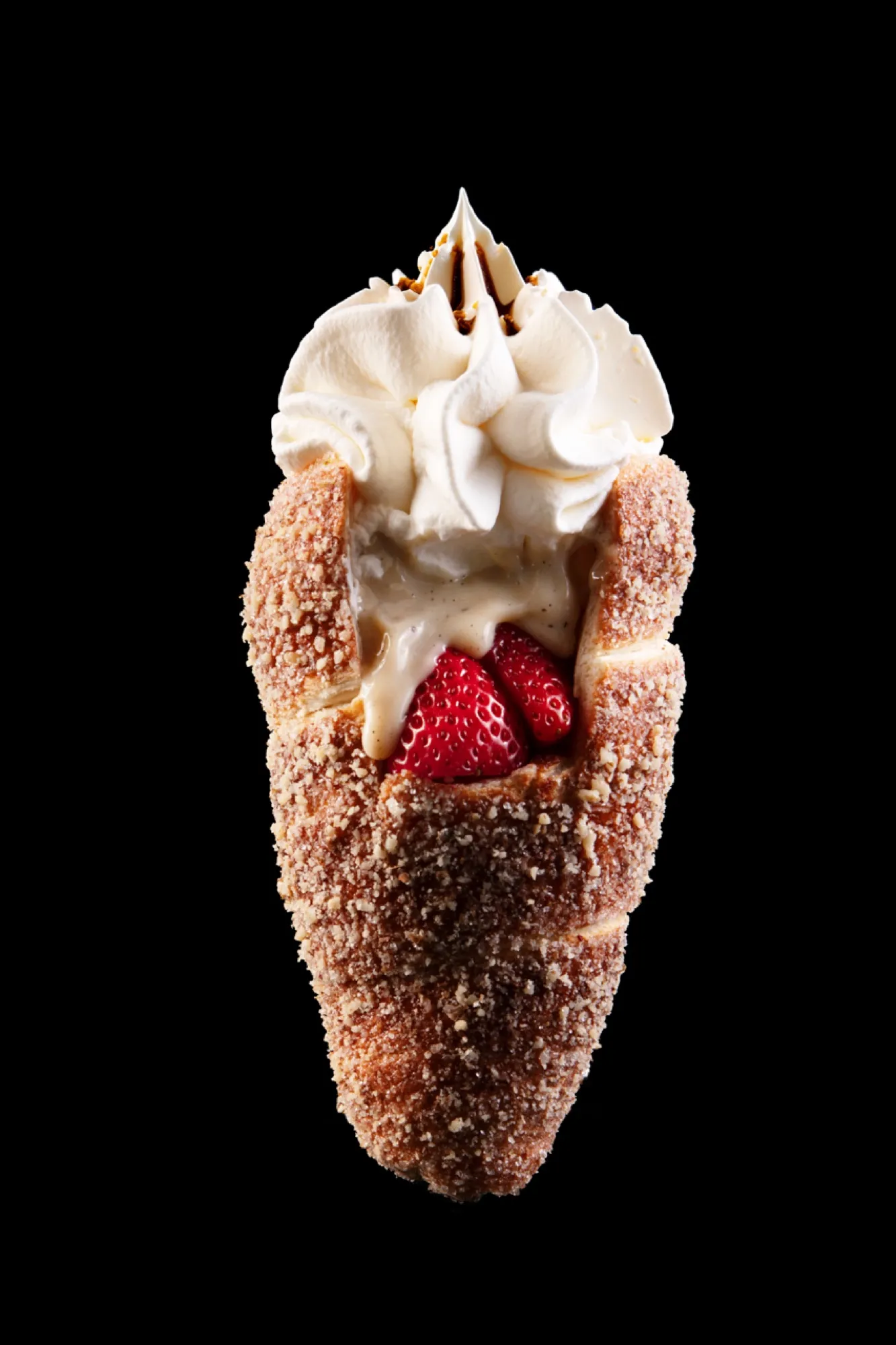 A chimney cake split open and filled with strawberries and whipped cream