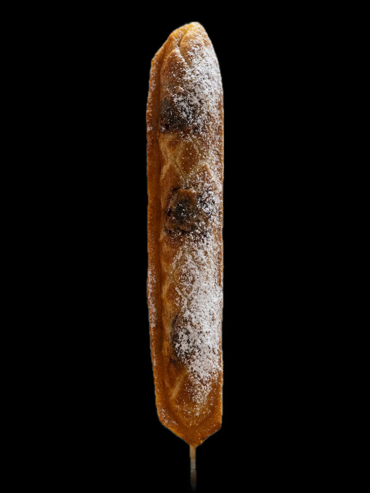 A long waffle on a stick with a melted Bounty bar inside, dusted with sugar
