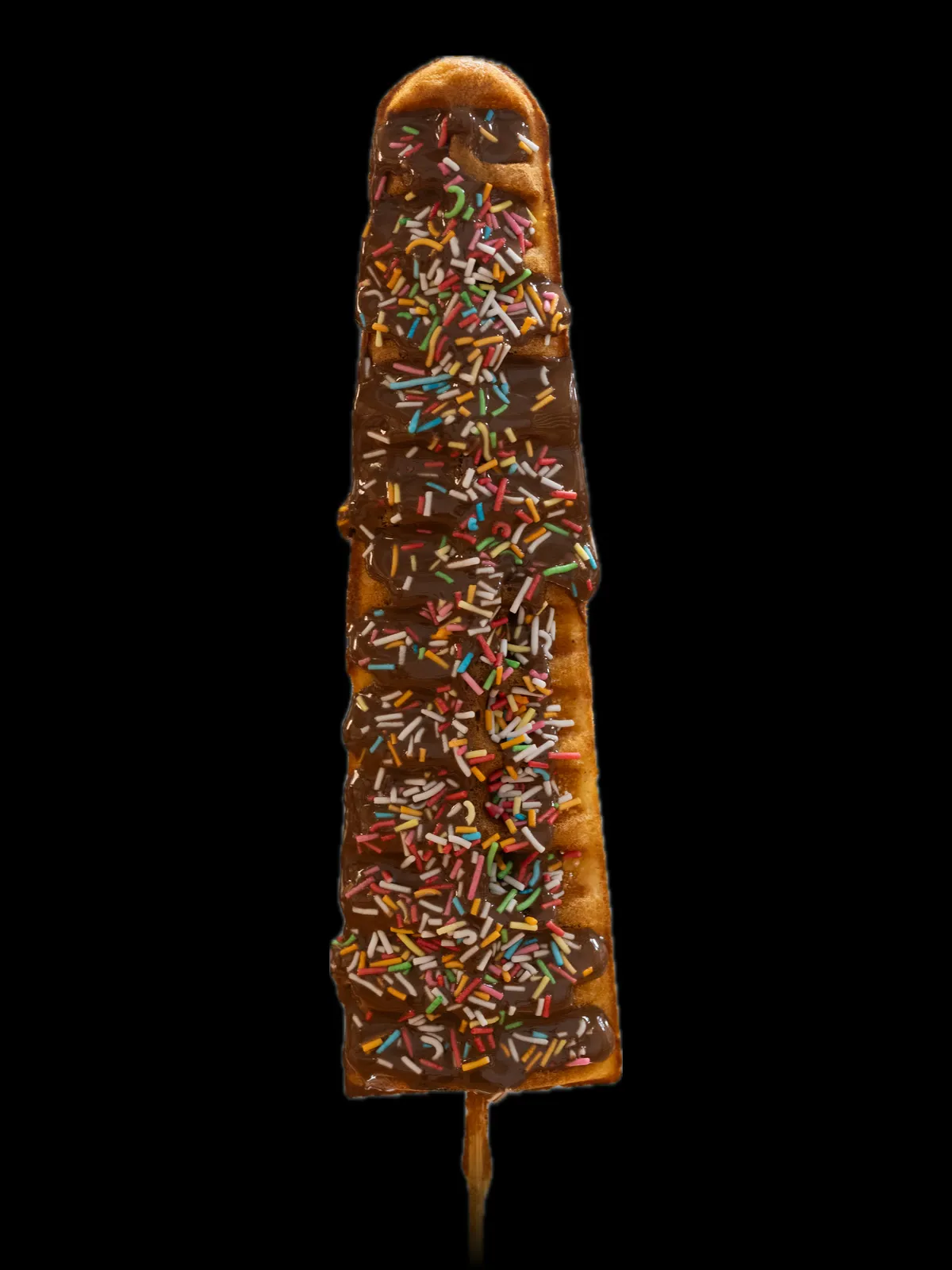A waffle on a stick spread with Nutella and rainbow sprinkles